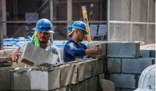 Workers building a CMU wall with mortar.